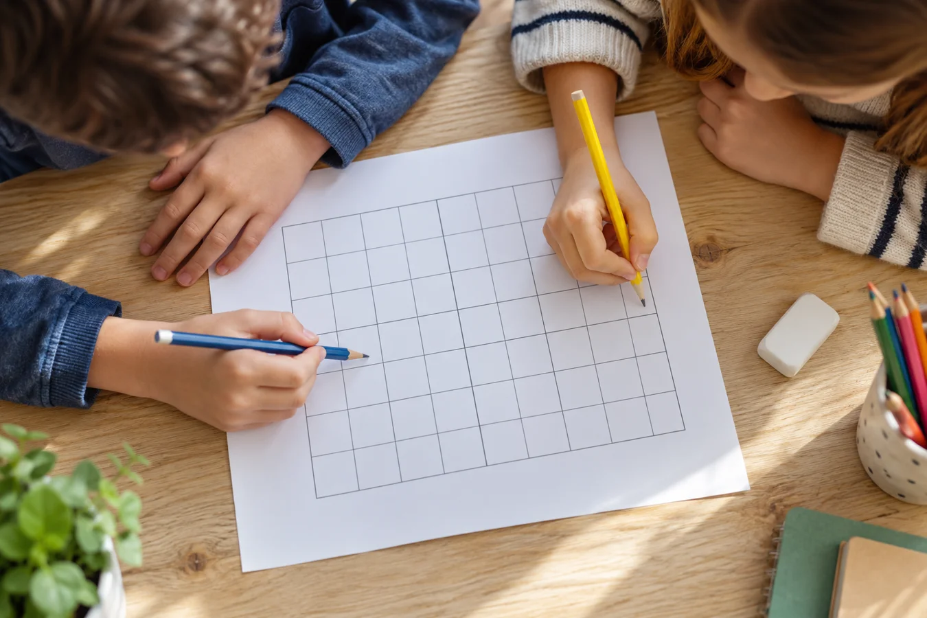 Deux enfants utilisent leurs crayons sur une feuille quadrillée