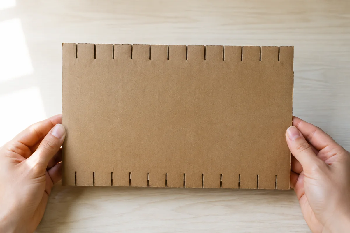 Étape 1 : carton cranté régulièrement par l’adulte, pour « Mini-tapisserie sans aiguille sur métier en carton ».