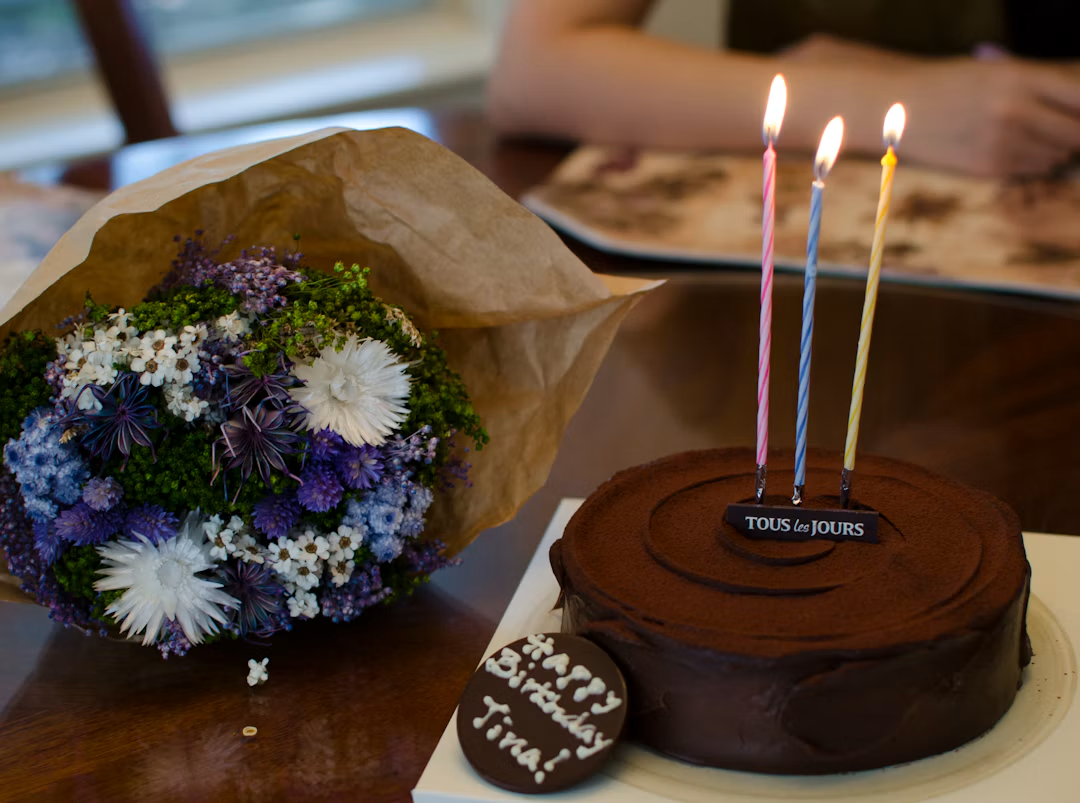 Bouquet de fleurs près d'un gâteau au chocolat avec des bougies d'anniversaire