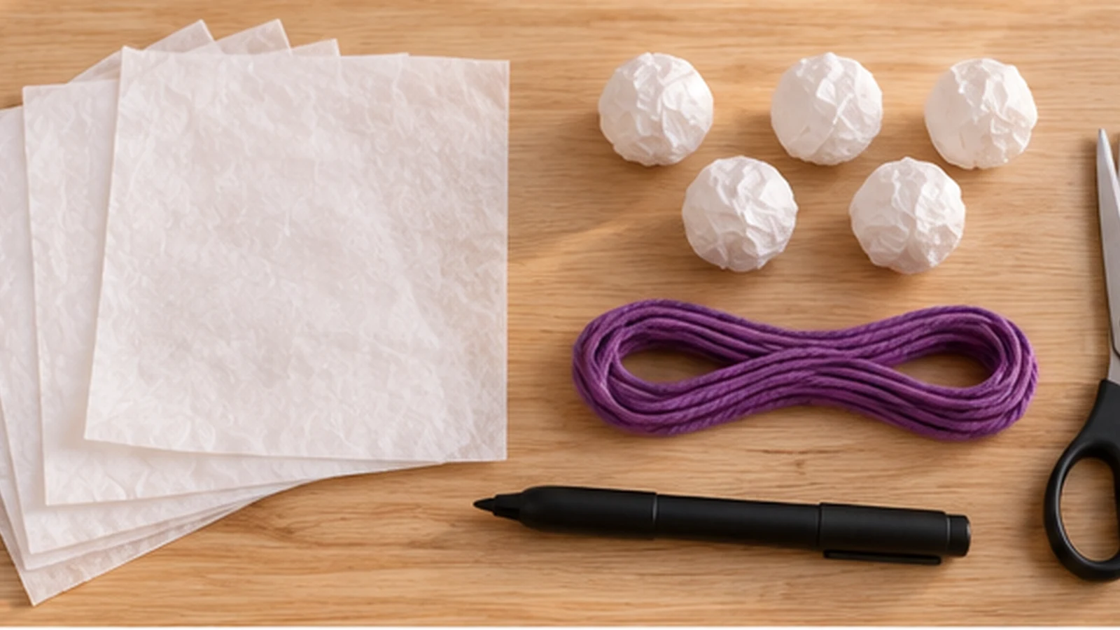Carré de papier de soie, petite boule froissée, cordon violet et feutre noir