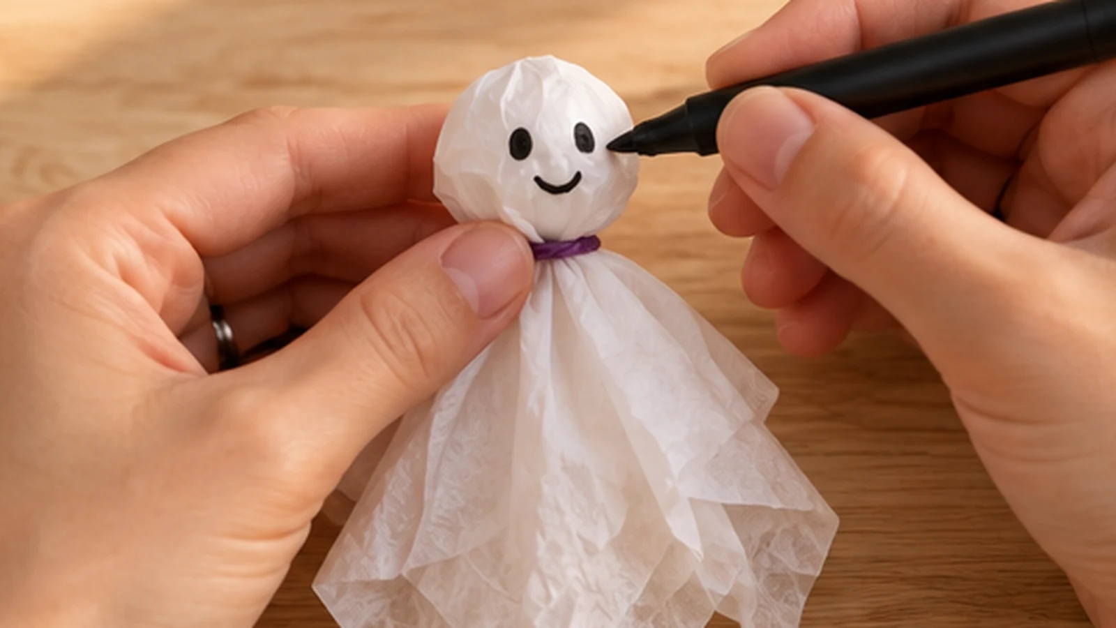 Visage souriant dessiné au feutre noir sur une tête de fantôme en papier de soie