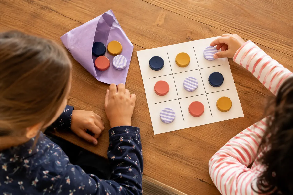 Enfants jouant au morpion sur papier et avec de gros bouchons colorés