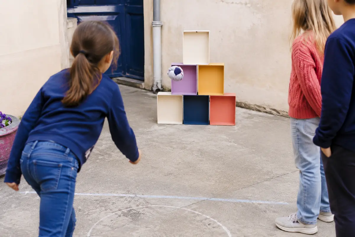 Enfants lançant une balle de chaussettes vers des boîtes en carton empilées